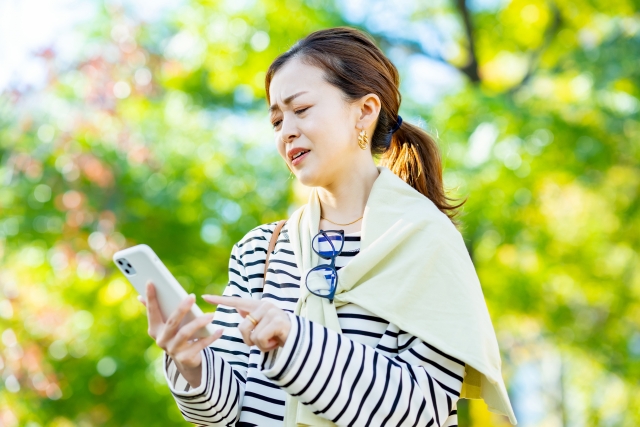 スマホを見てしかめっ面をする女性